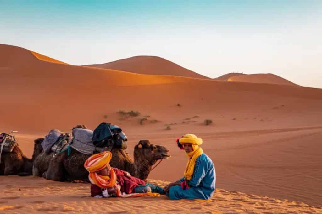 deux berberes et leurs chameaux dans le desert du sahara au maroc