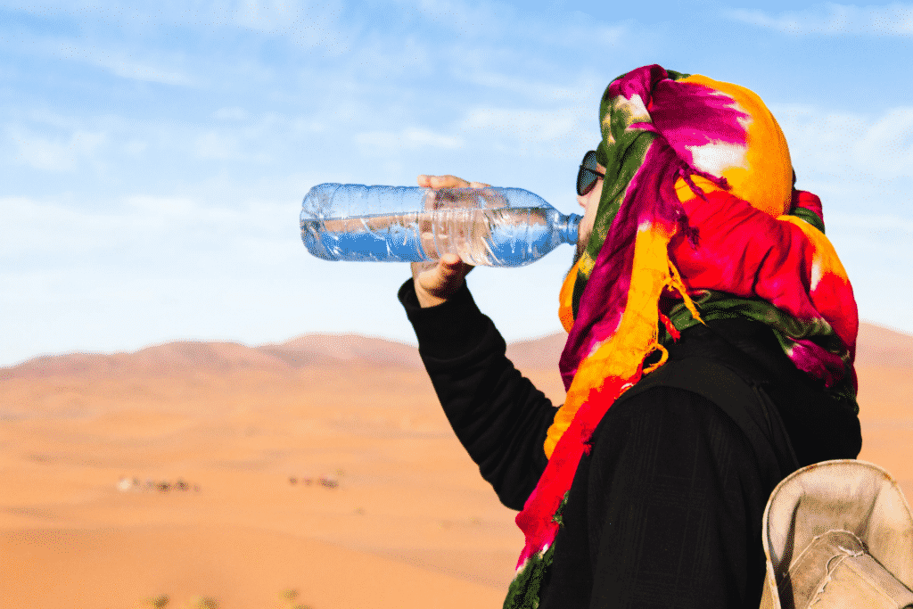 touriste qui boit de l´eau en bouteille dans le desert au maroc