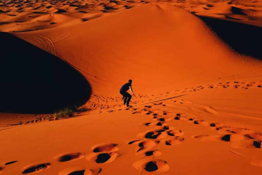 homme faisant du sandborad dans le desert de merzouga au maroc