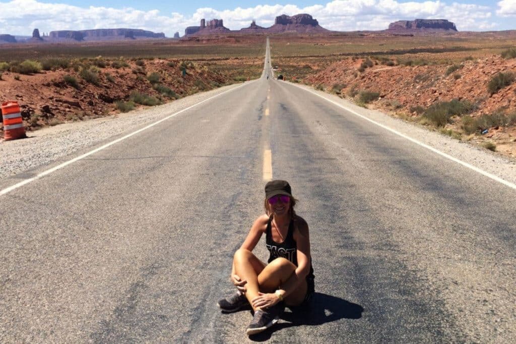 route des USA avec une touristes assise par terre