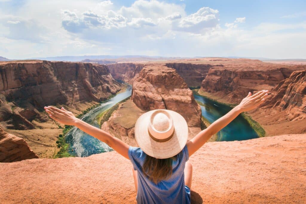 jeune femme assise devant le grand canyon aux États-Unis et ouvrant les bras